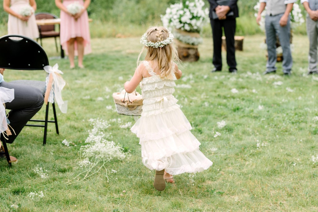 Cute flower girl running down the aisle at Heather Mountain Lodge Golden BC wedding