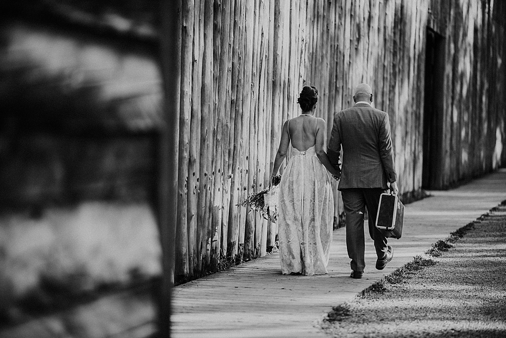 bride-and-groom-walking-hand-in-hand-with-suitcase